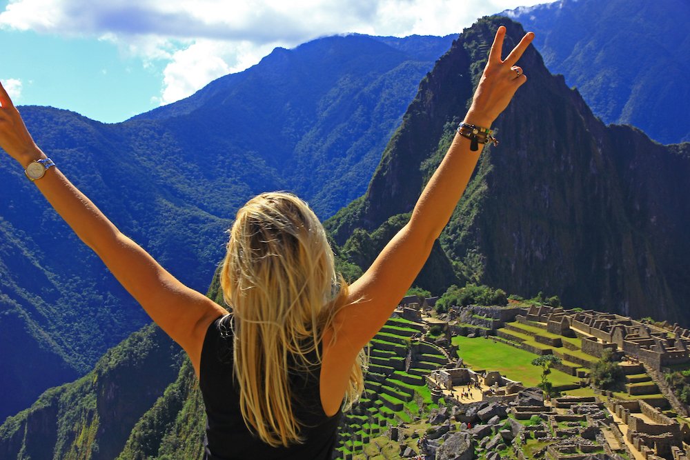 Young woman with raised arms on background of Machu Picchu. Ancient inca city,Peru