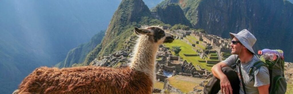 a man and a llama in front of machu picchu